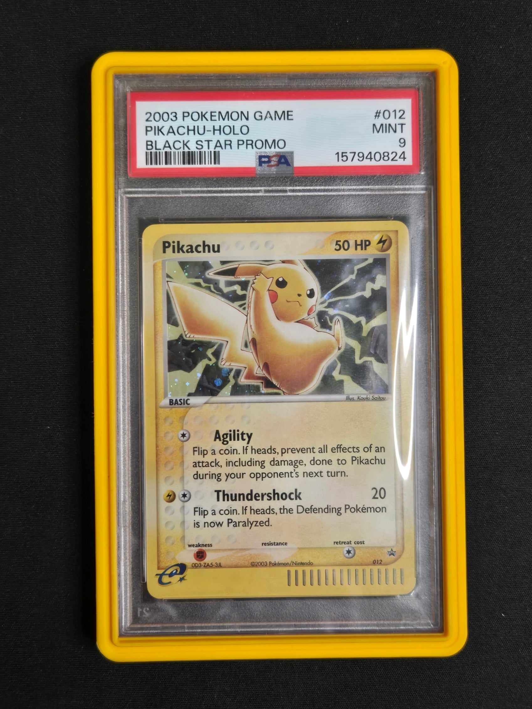 A graded 2003 Pokémon Game Pikachu-holo promo card in a clear PSA slab with a yellow border, photographed against a black background.