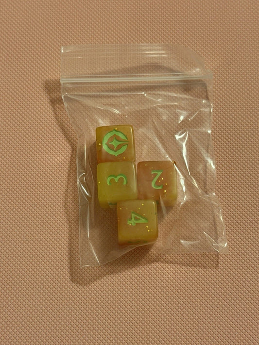 Set of four dice with green numbers on a clear plastic bag against a beige background