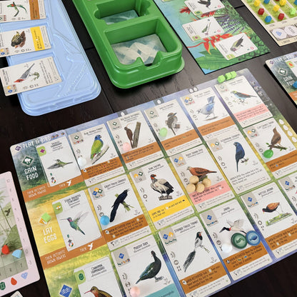 Board game cards with bird illustrations on a wooden surface